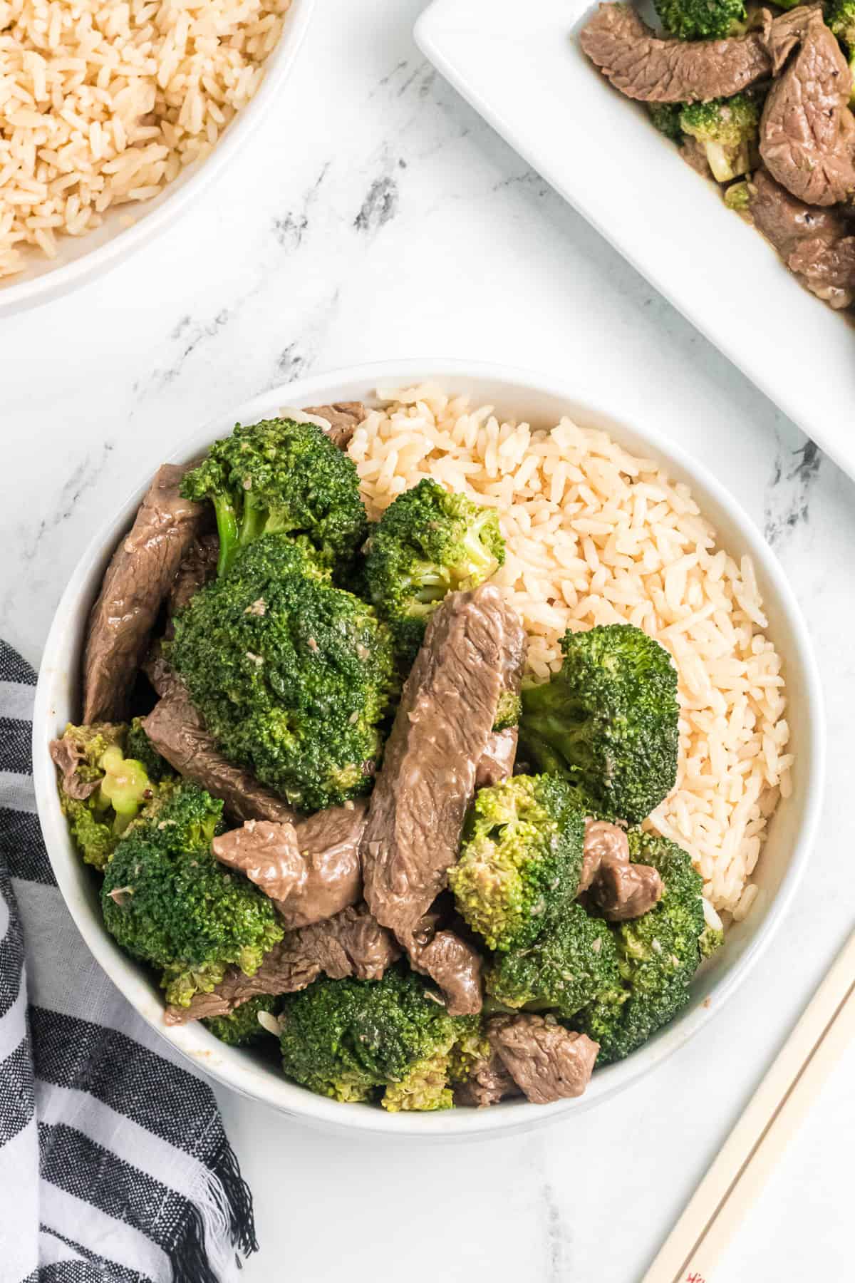 A bowl of rice with chunks of beef and broccoli in sauce.