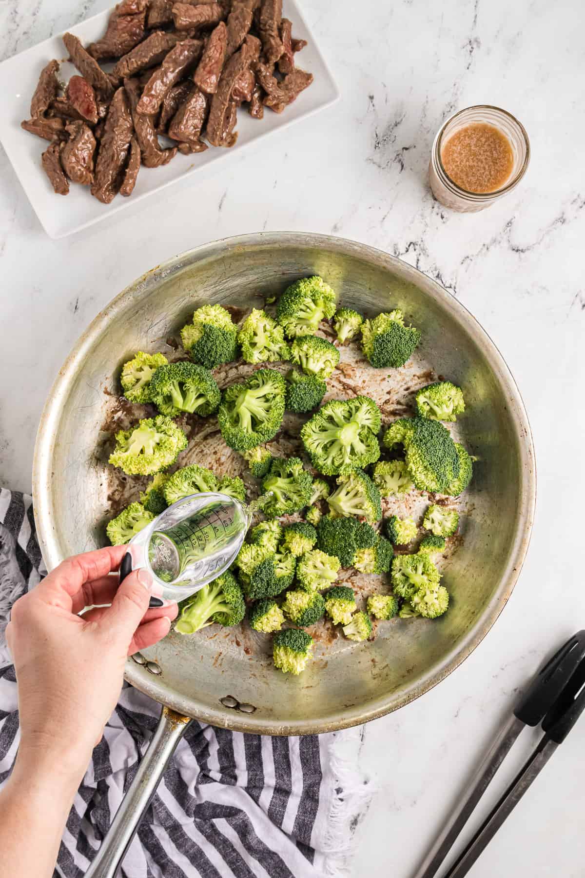 Adding water to a pan of broccoli.