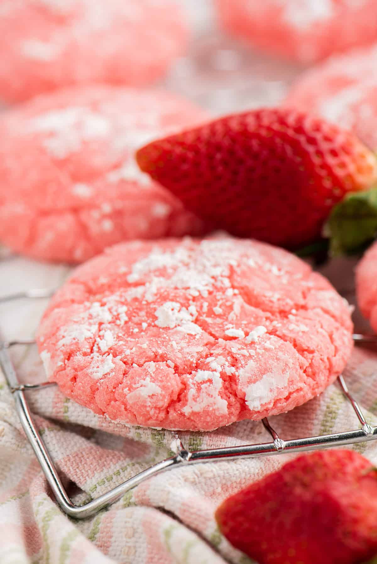 A strawberry cake mix cookie cooling on a wire rack.