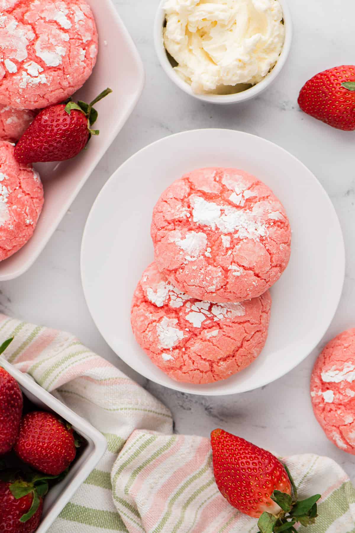Strawberry cake mix cookies next to strawberries and cream cheese filling.