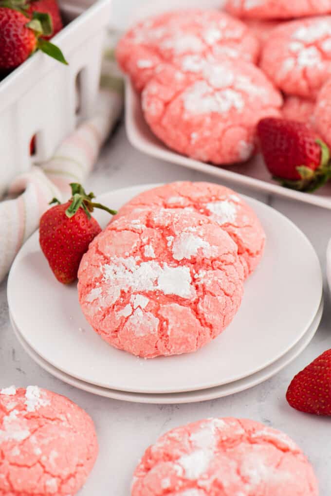 Two pink strawberry cake mix cookies on a white plate.