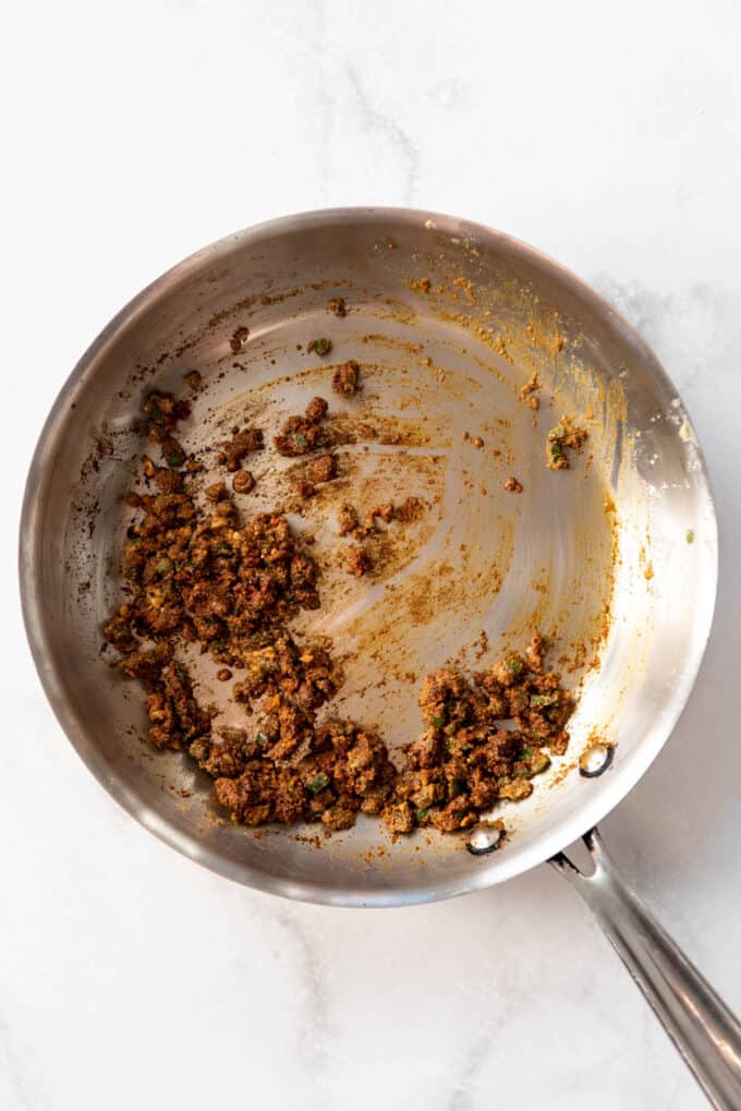 Cooking spices in a large skillet with butter, garlic, and jalapeno.