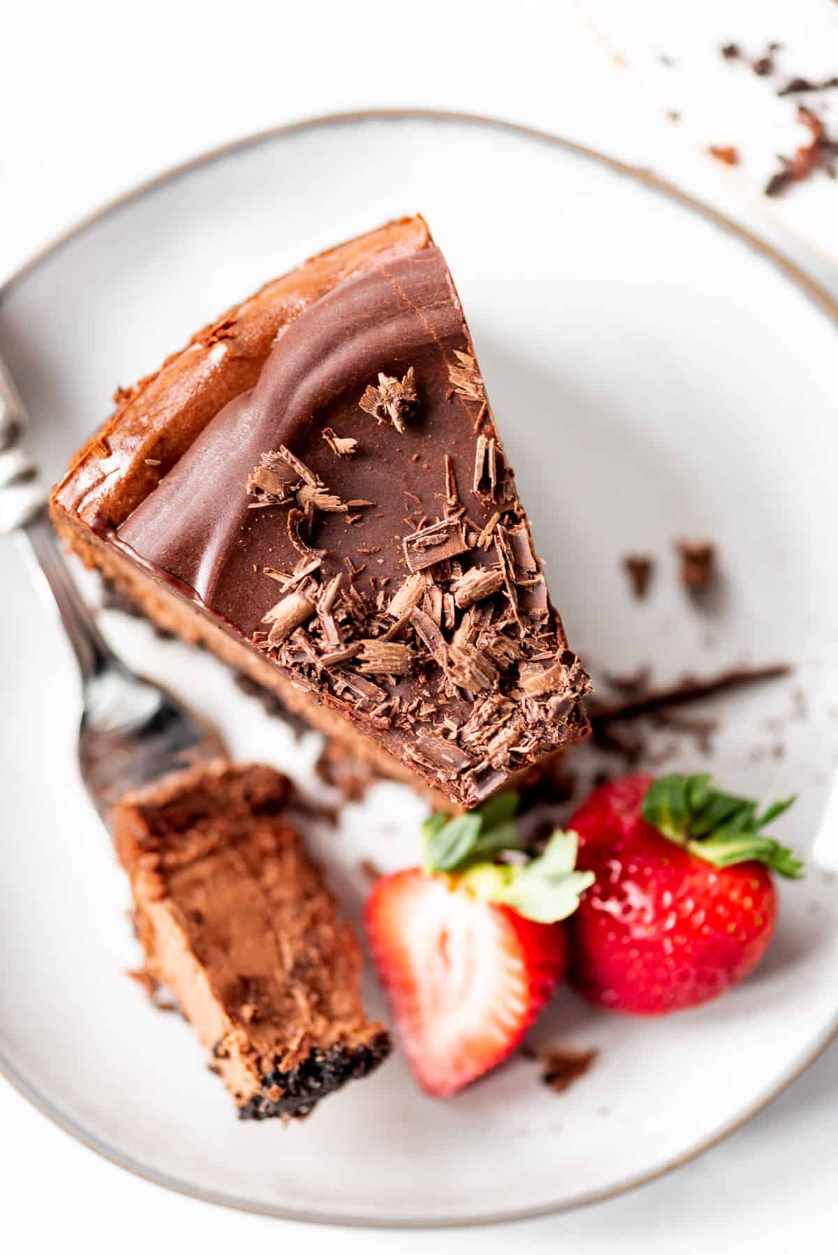 Triple Chocolate Cheesecake, bite on the fork, with strawberries.