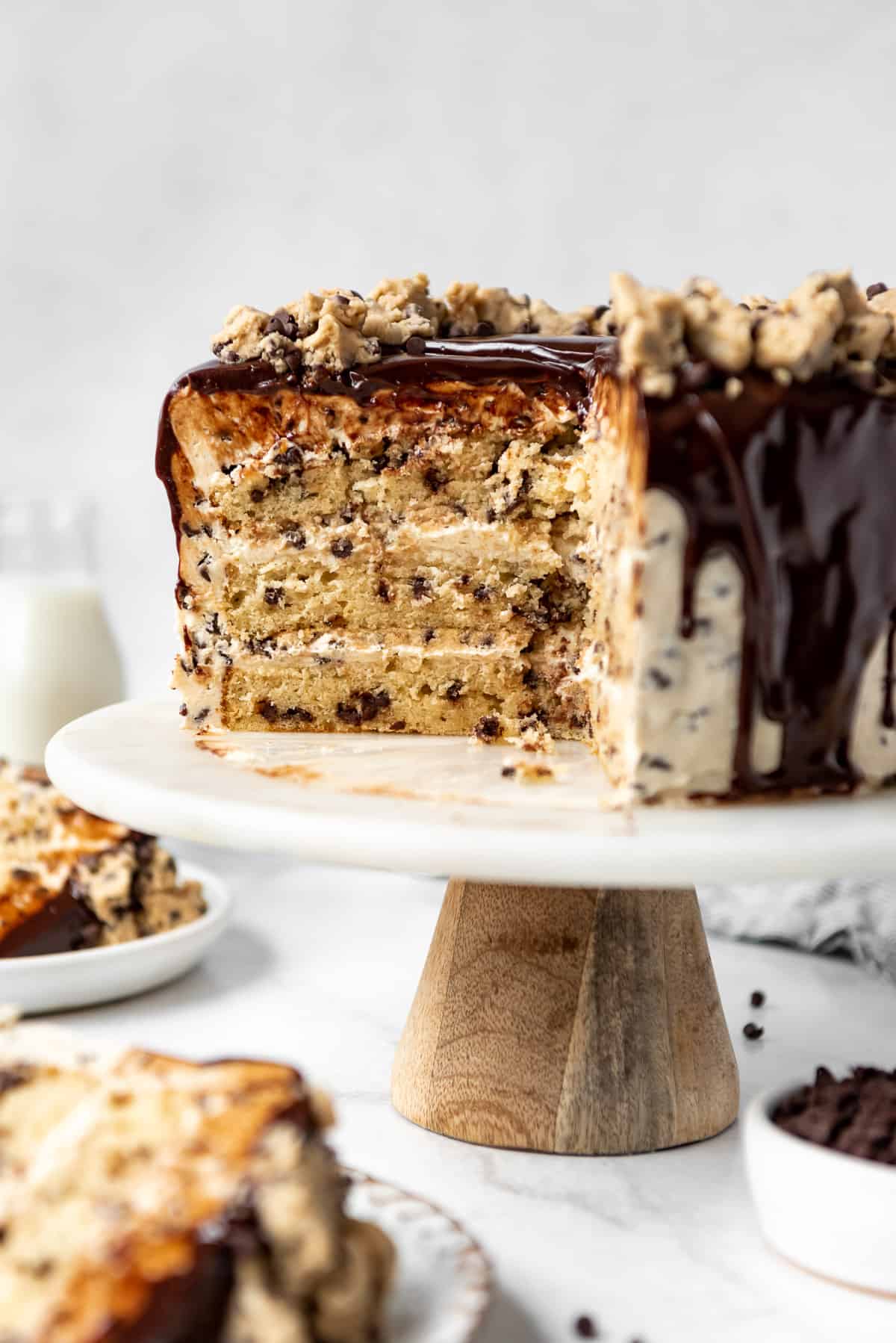 A three-layer chocolate chip cookie dough cake that has been sliced into showing the layers on a cake stand.