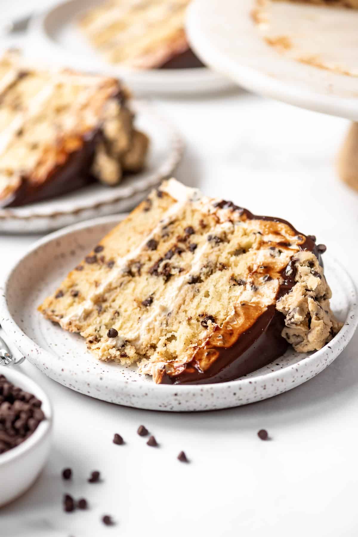 A piece of chocolate chip cookie dough cake laying flat on its side on a plate.