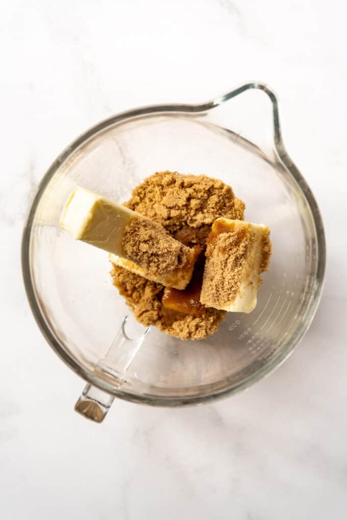 Sticks of butter, brown sugar, and vanilla extract in a large glass bowl.