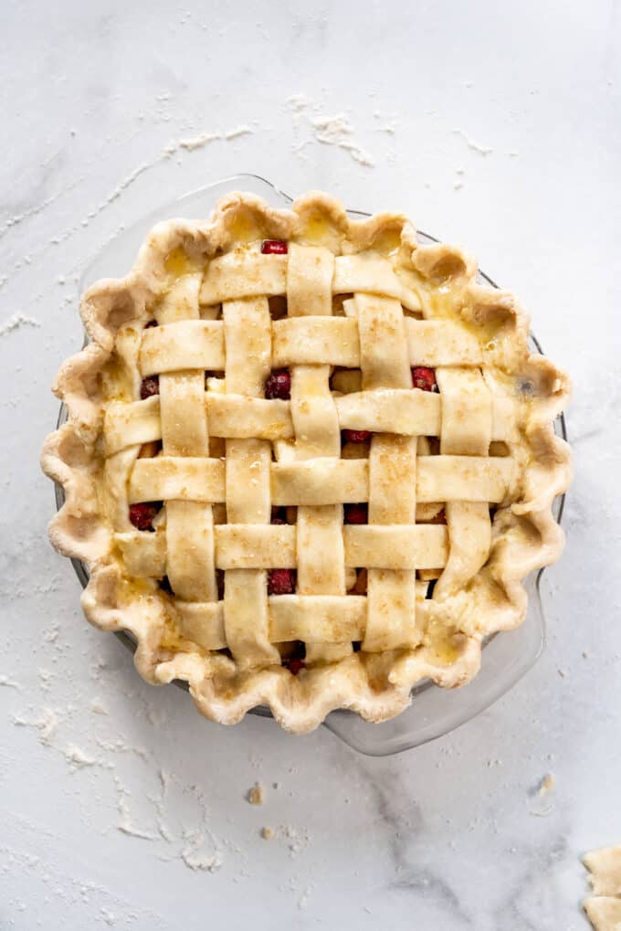 An unbaked pie with a lattice pie crust sprinkled with coarse turbinado sugar.