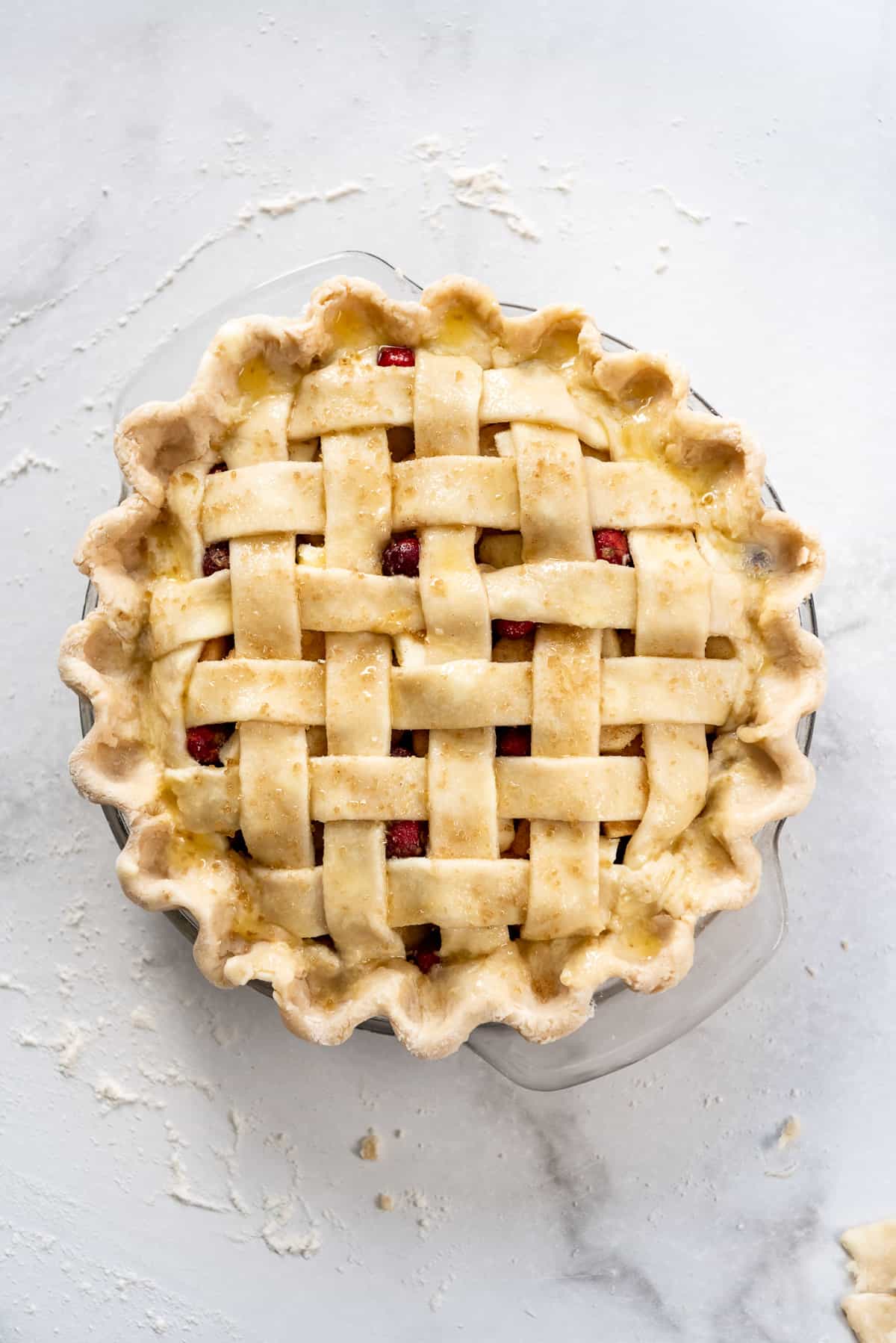 An unbaked pie with a lattice pie crust sprinkled with coarse turbinado sugar.