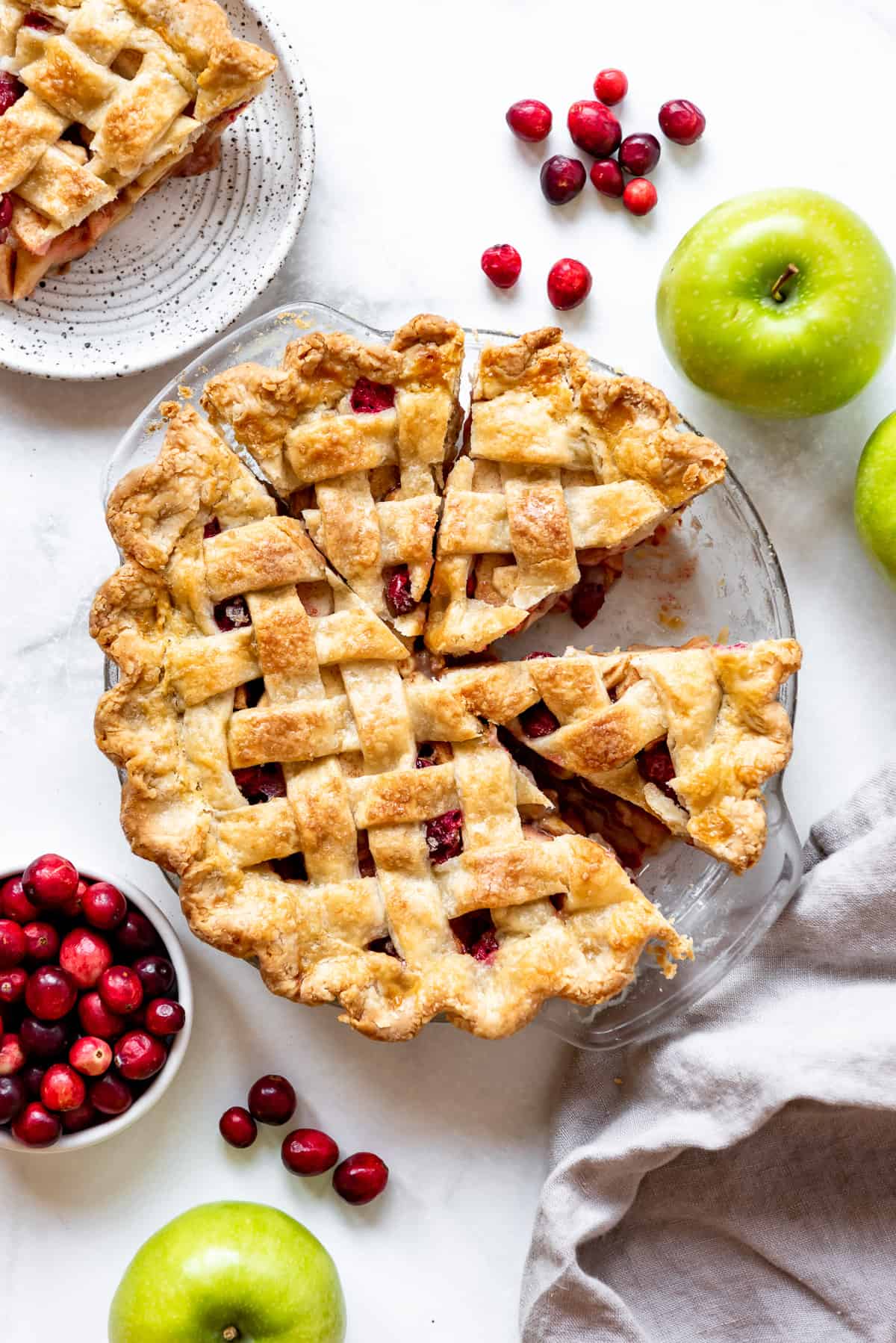 A lattice pie crust on top of a cranberry apple pie filling.