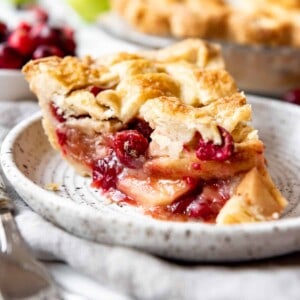 A slice of cranberry apple pie on a plate.