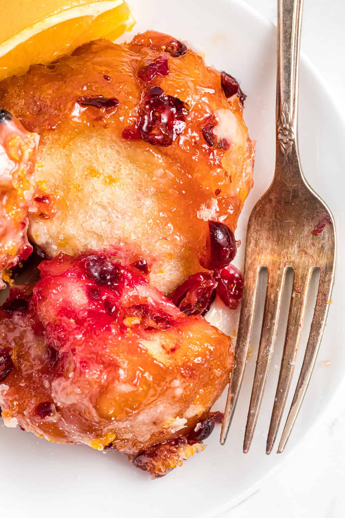 A fork on a plate next to cranberry orange monkey bread sweet rolls.