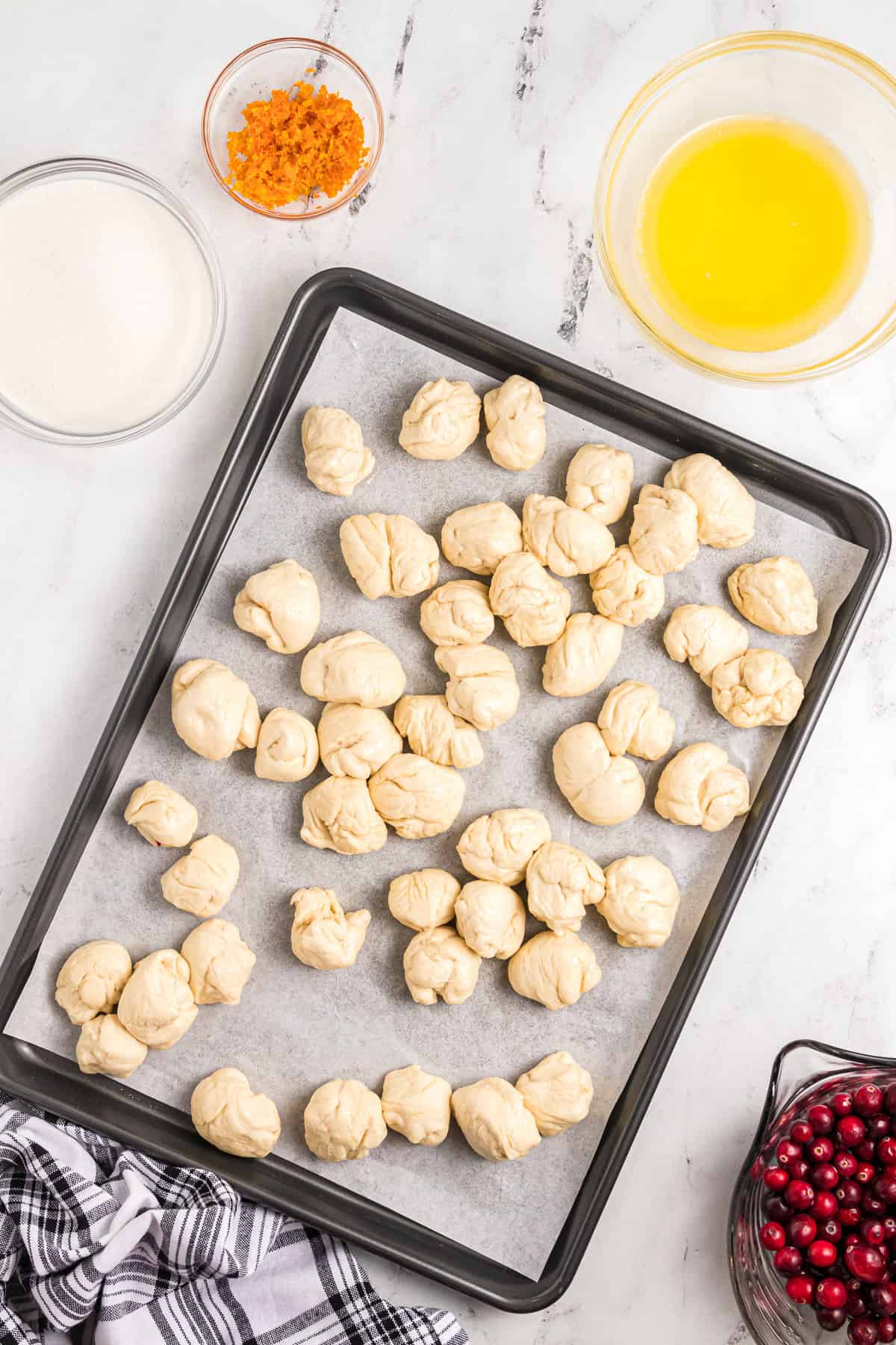 Pieces of bread dough on a baking sheet lined with parchment paper.