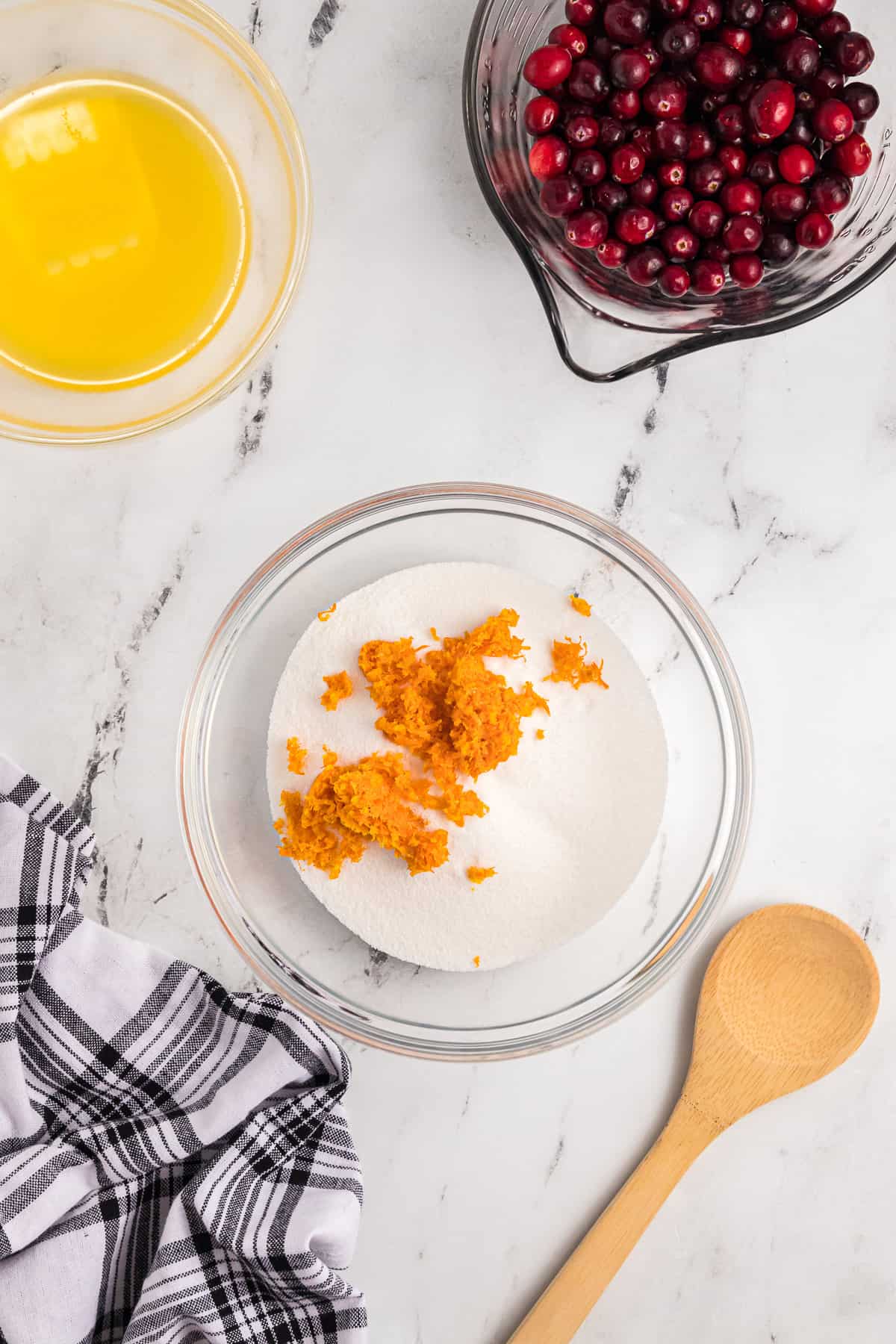 Adding orange zest to a bowl of granulated sugar.