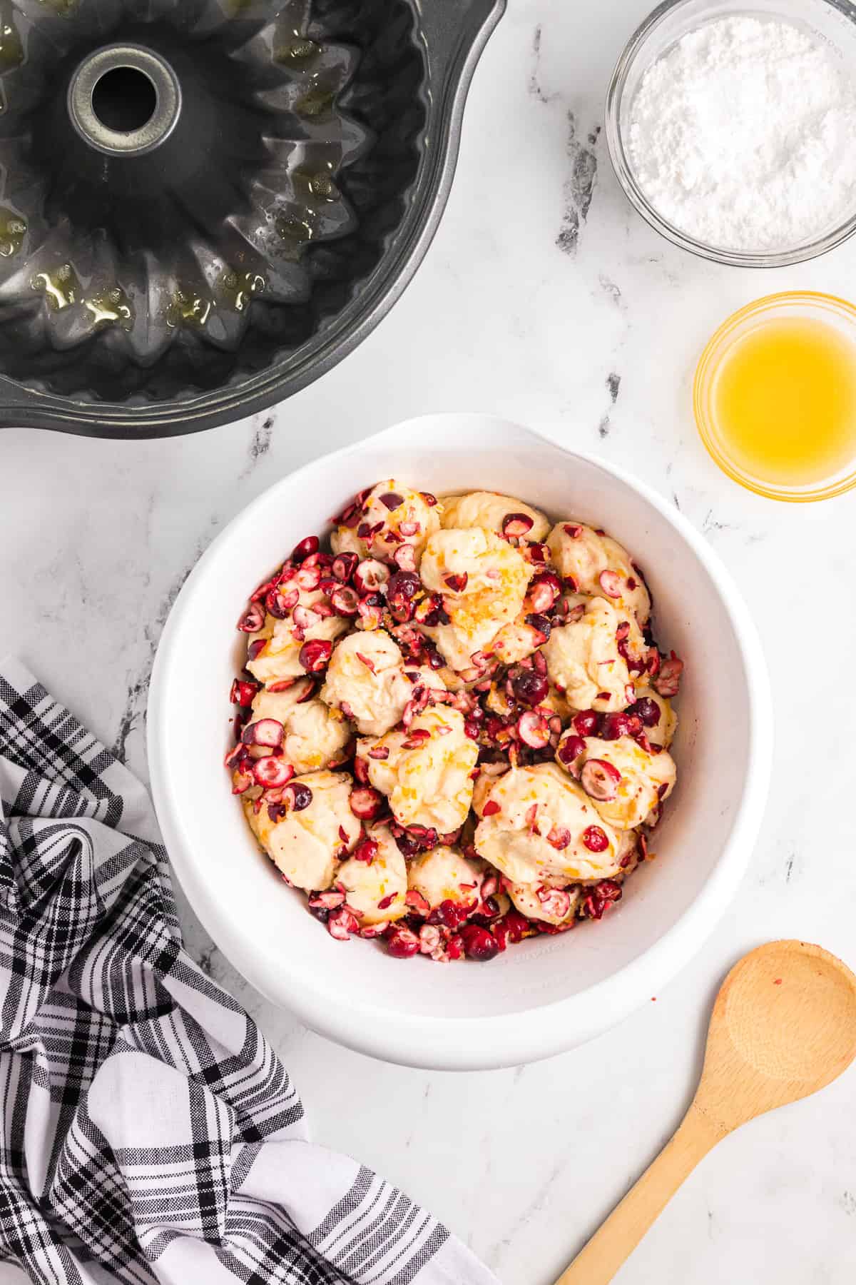 A bowl full of roll dough with chopped fresh cranberries, orange zest, and sugar.