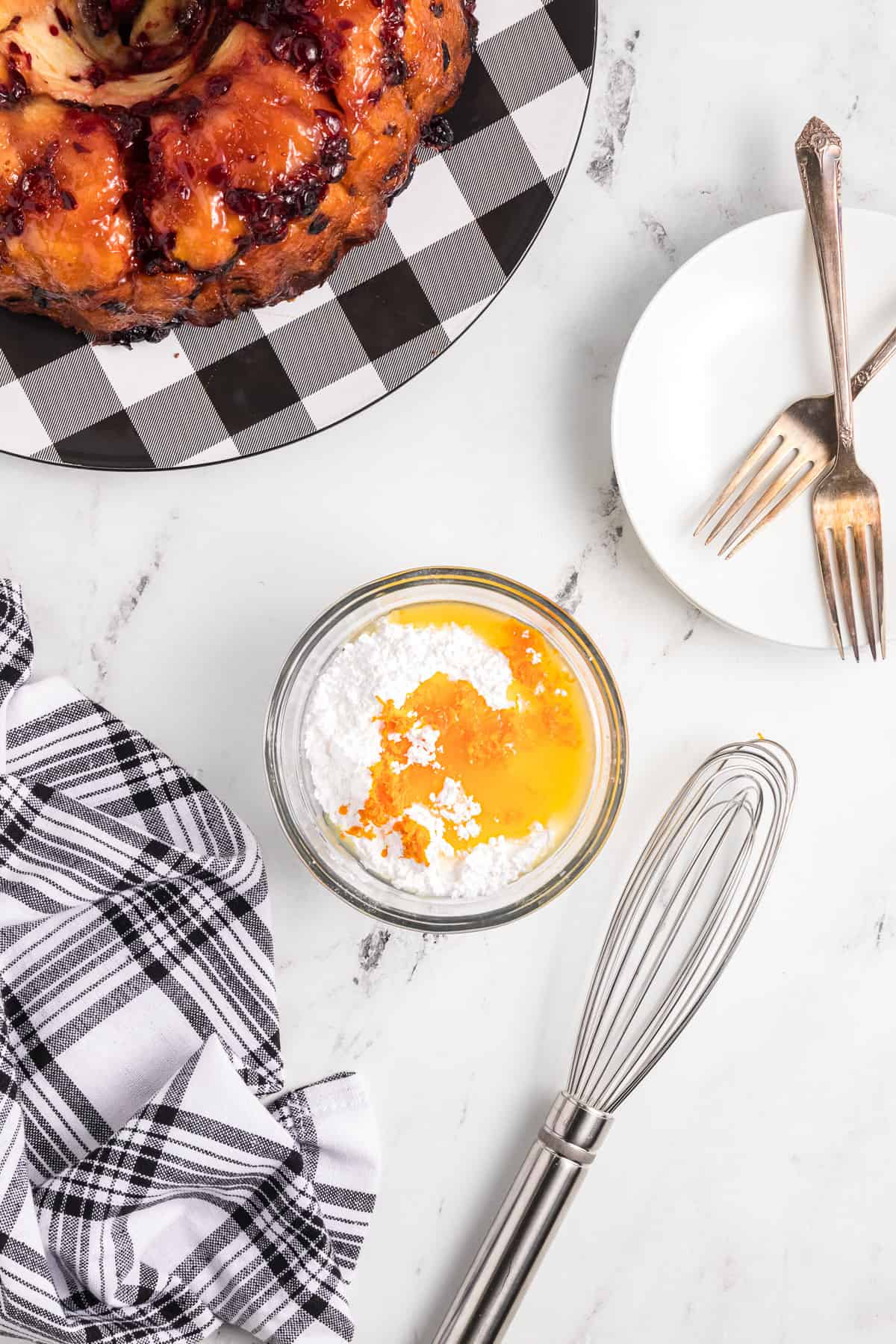 Powdered sugar in a bowl with orange juice and orange zest.