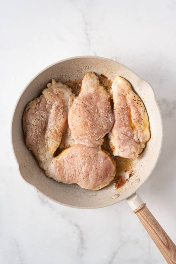 Searing chicken cutlets dredged in flour in a pan with oil and butter.