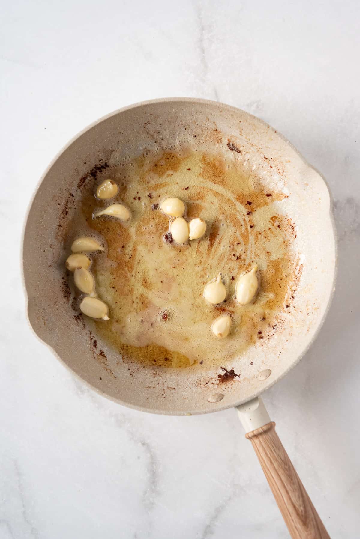 Sauteeing whole garlic cloves in a pan with butter and oil.