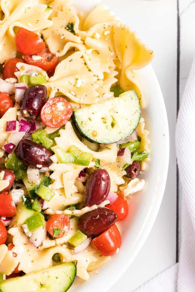 Fresh slices of cucumbers and tomatoes in a Greek pasta salad with olives and feta cheese.