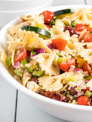 A serving bowl filled with summer pasta salad.