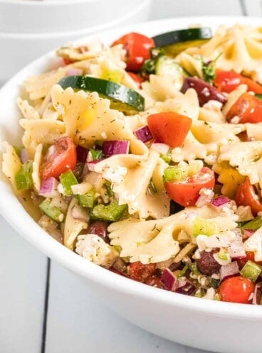 A serving bowl filled with summer pasta salad.