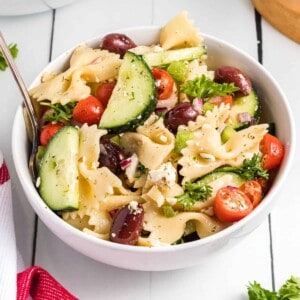A white bowl filled with Greek pasta salad.