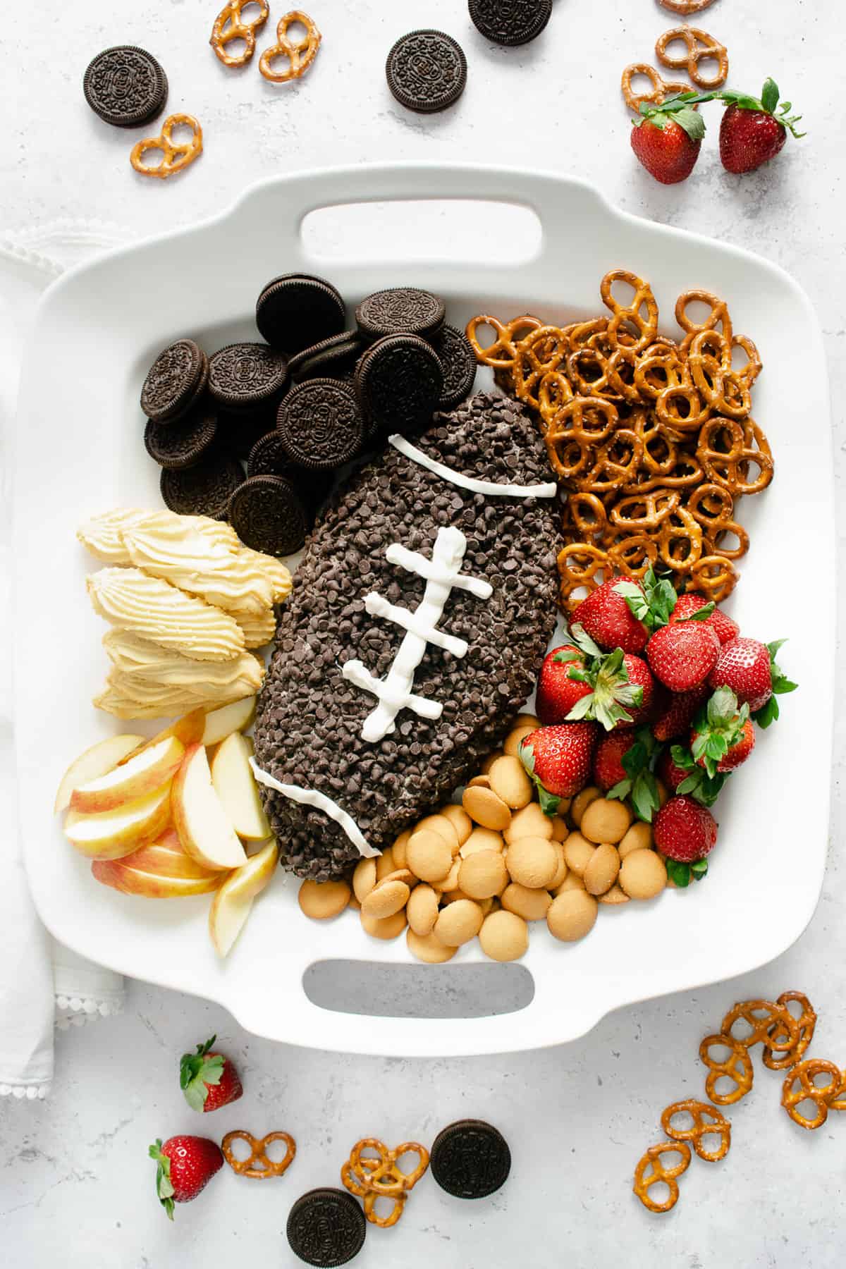 A football shaped dessert cheese ball covered in mini chocolate chips and decorated to look like a football.