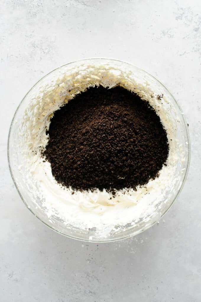 Adding chocolate cookie crumbs to cream cheese, butter, and powdered sugar.