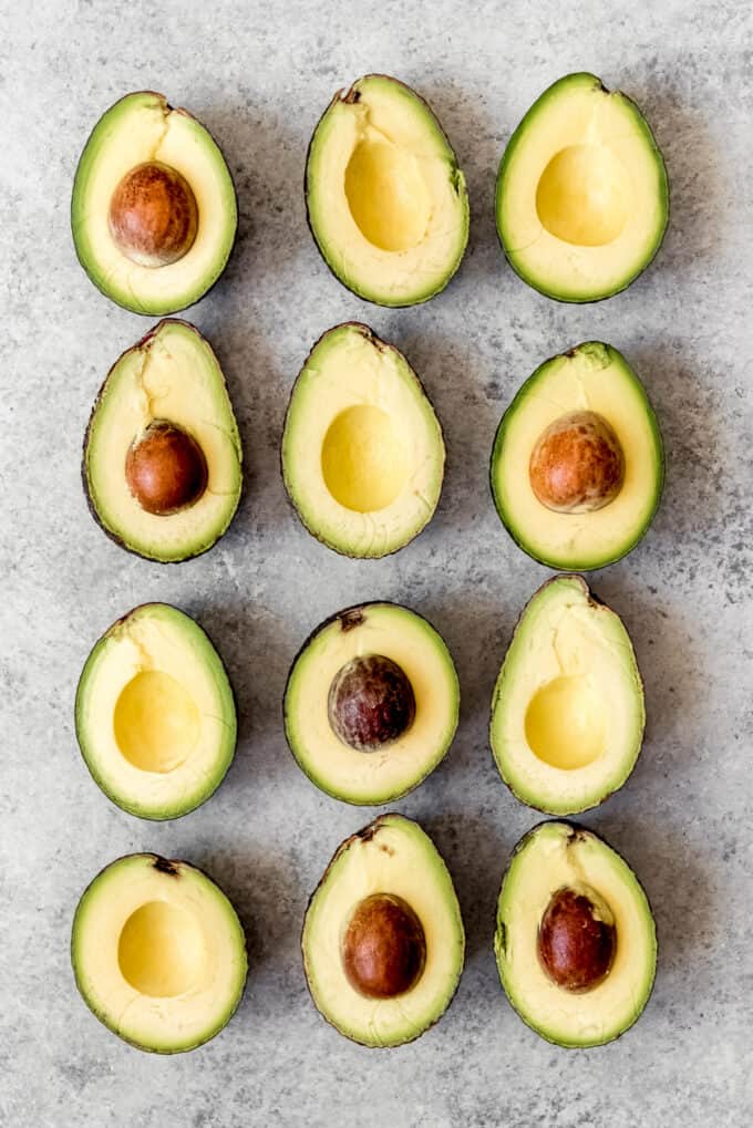 An image of ripe avocados sliced open and arranged in a grid pattern.