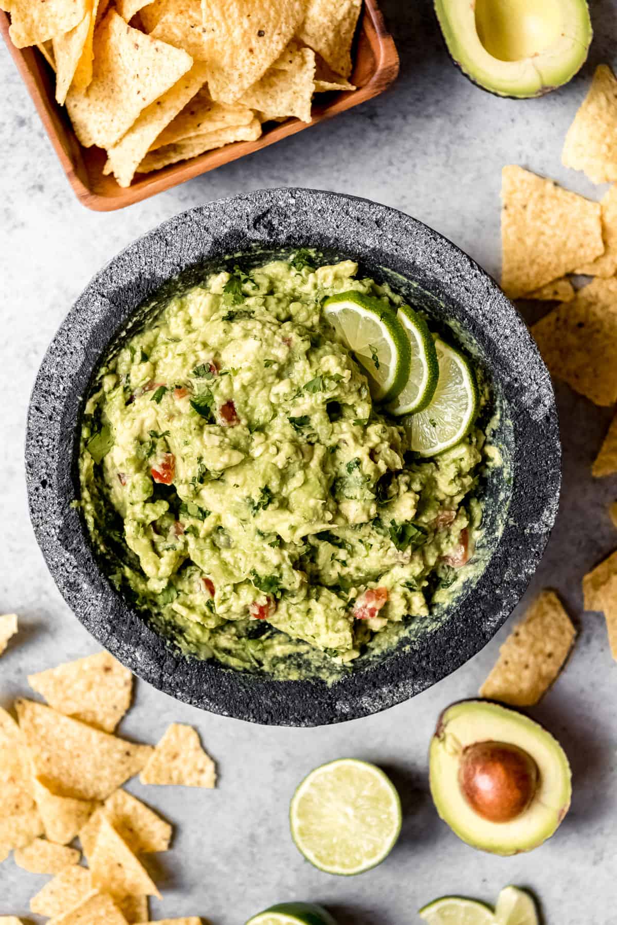 An image of a big bowl of guacamole garnished with sliced limes.