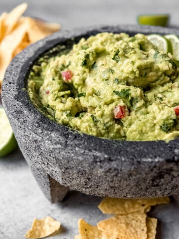 a bowl of homemade guacamole surrounded by tortilla chips
