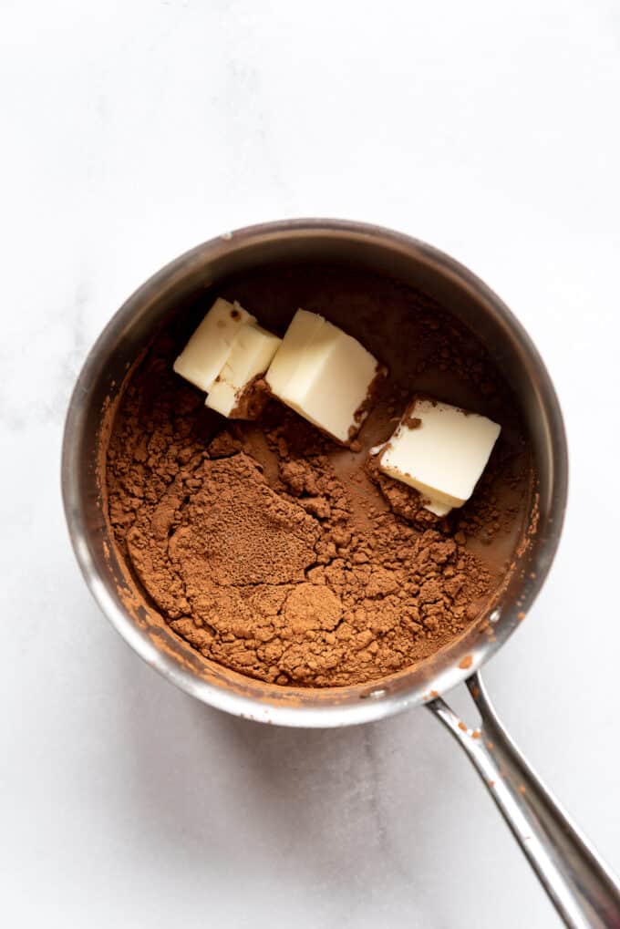 A saucepan with sugar, milk, cocoa powder, and butter.