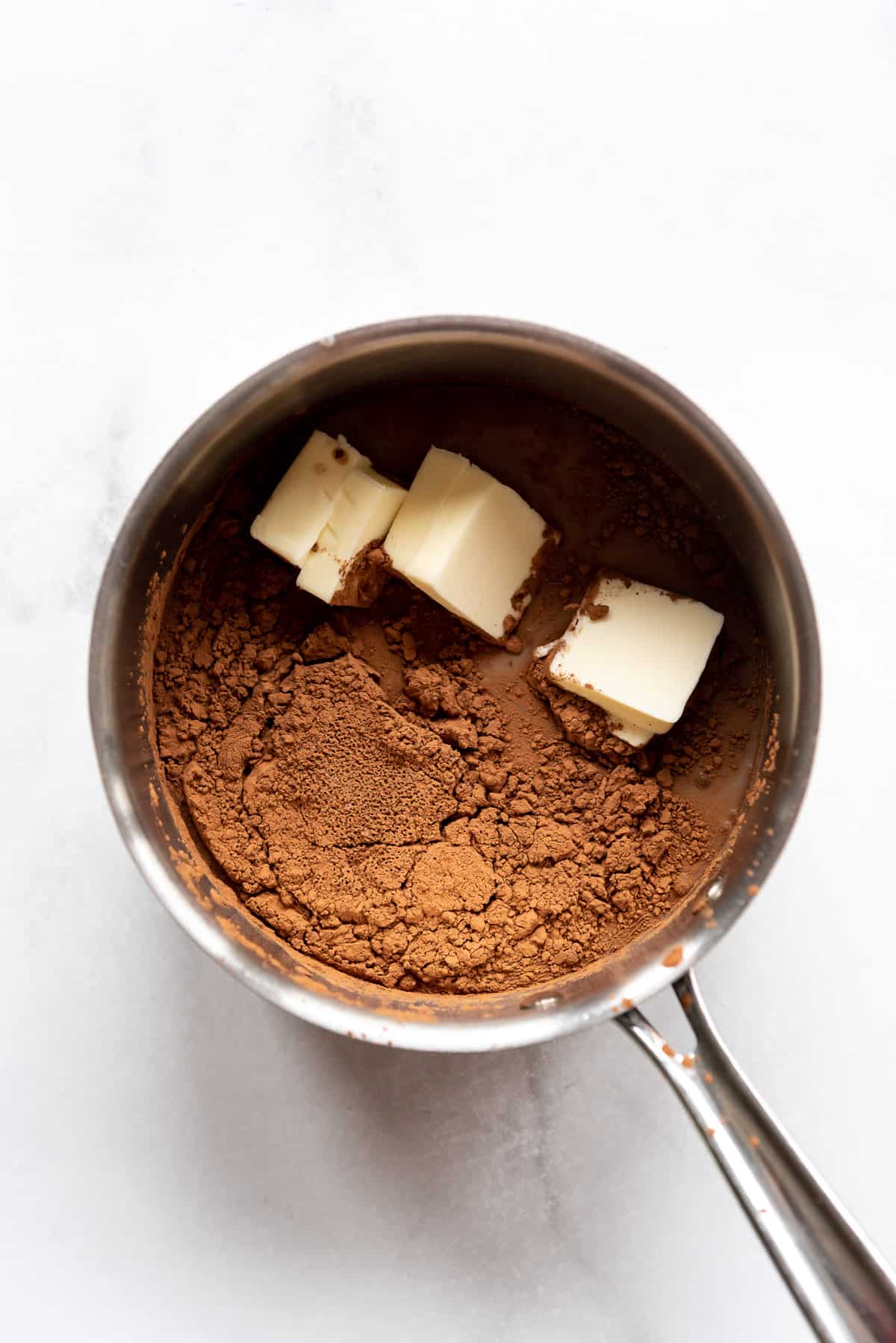 A saucepan with sugar, milk, cocoa powder, and butter.