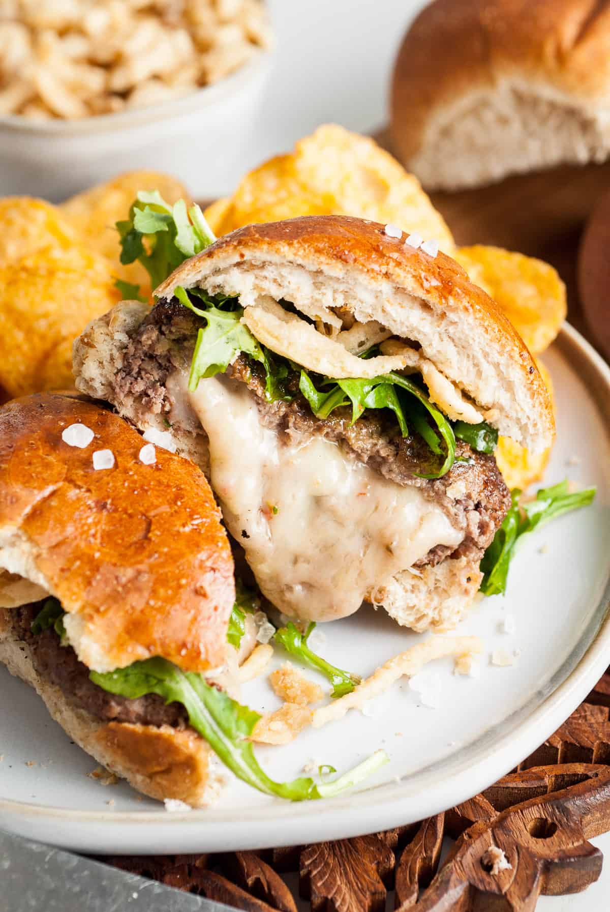 Half of a juicy lucy hamburger with melted pepper jack cheese oozing out of the middle on a plate.