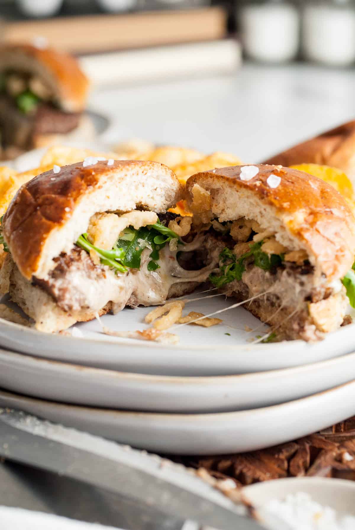 A juicy lucy hamburger cut open on a plate to reveal the cheesy center.