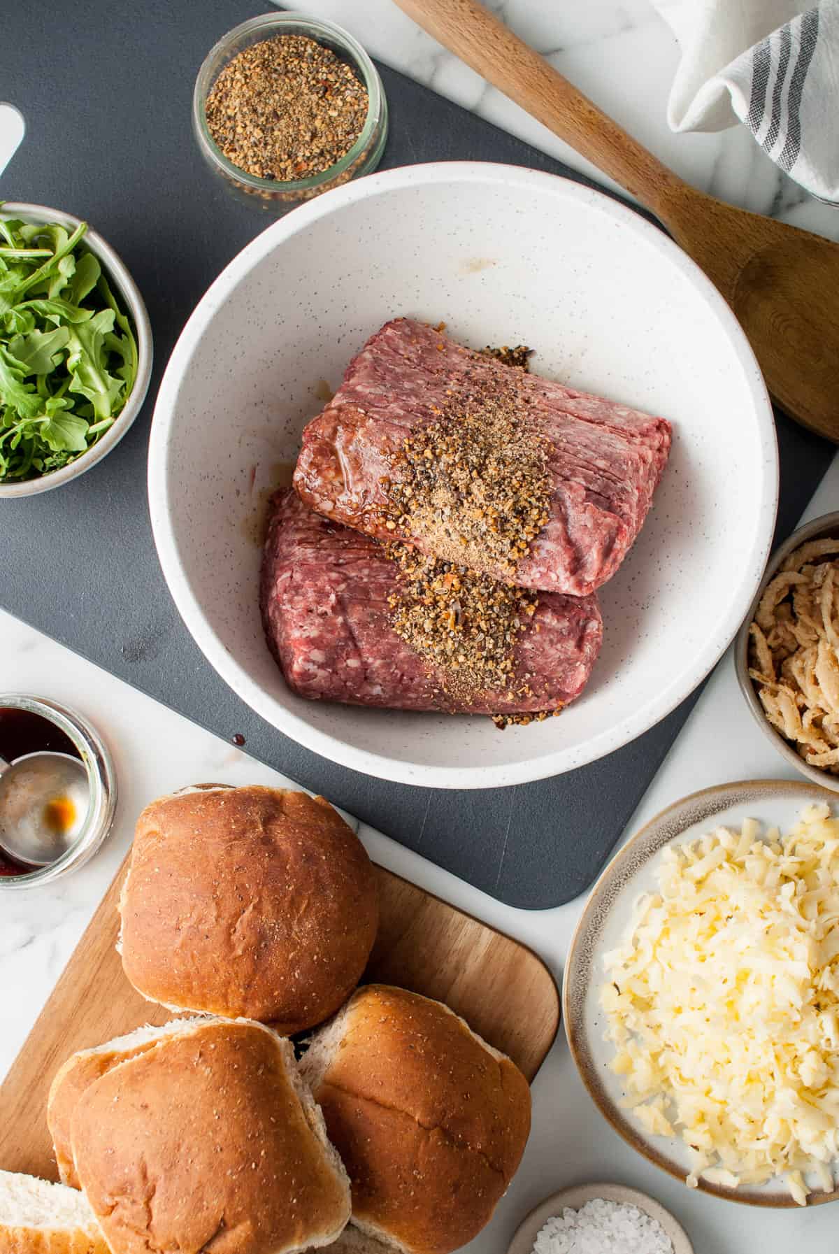 Adding seasoning to ground beef in a bowl.