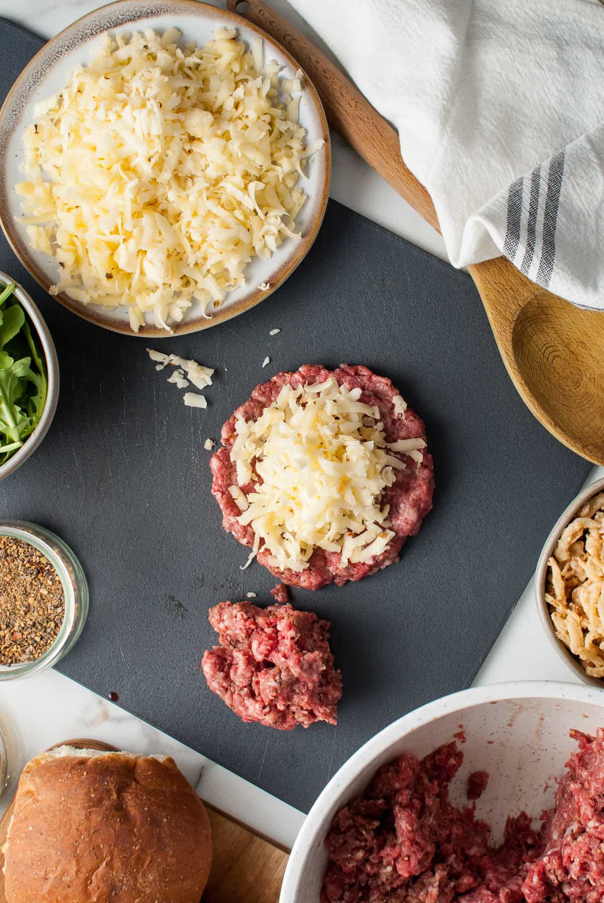 Shredded pepper jack cheese piled on top of seasoned ground beef to make a juicy lucy hamburger patty.