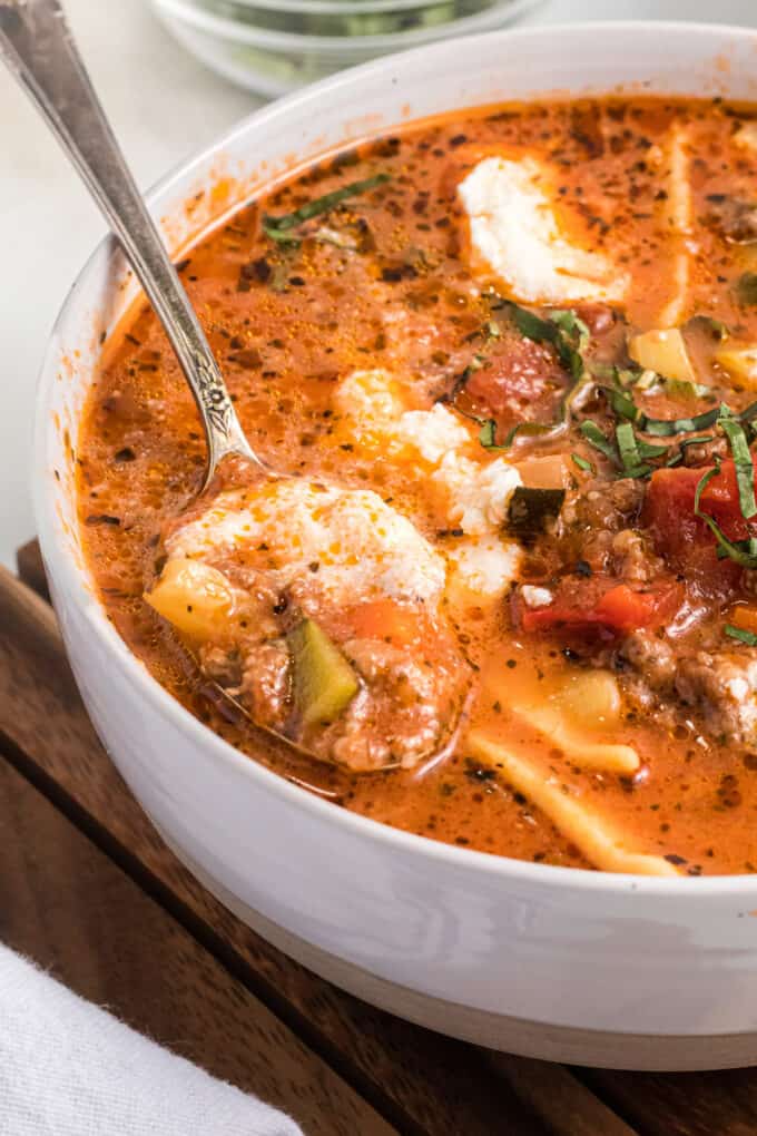 A close image of a spoonful of lasagna soup with ricotta cheese and vegetables.