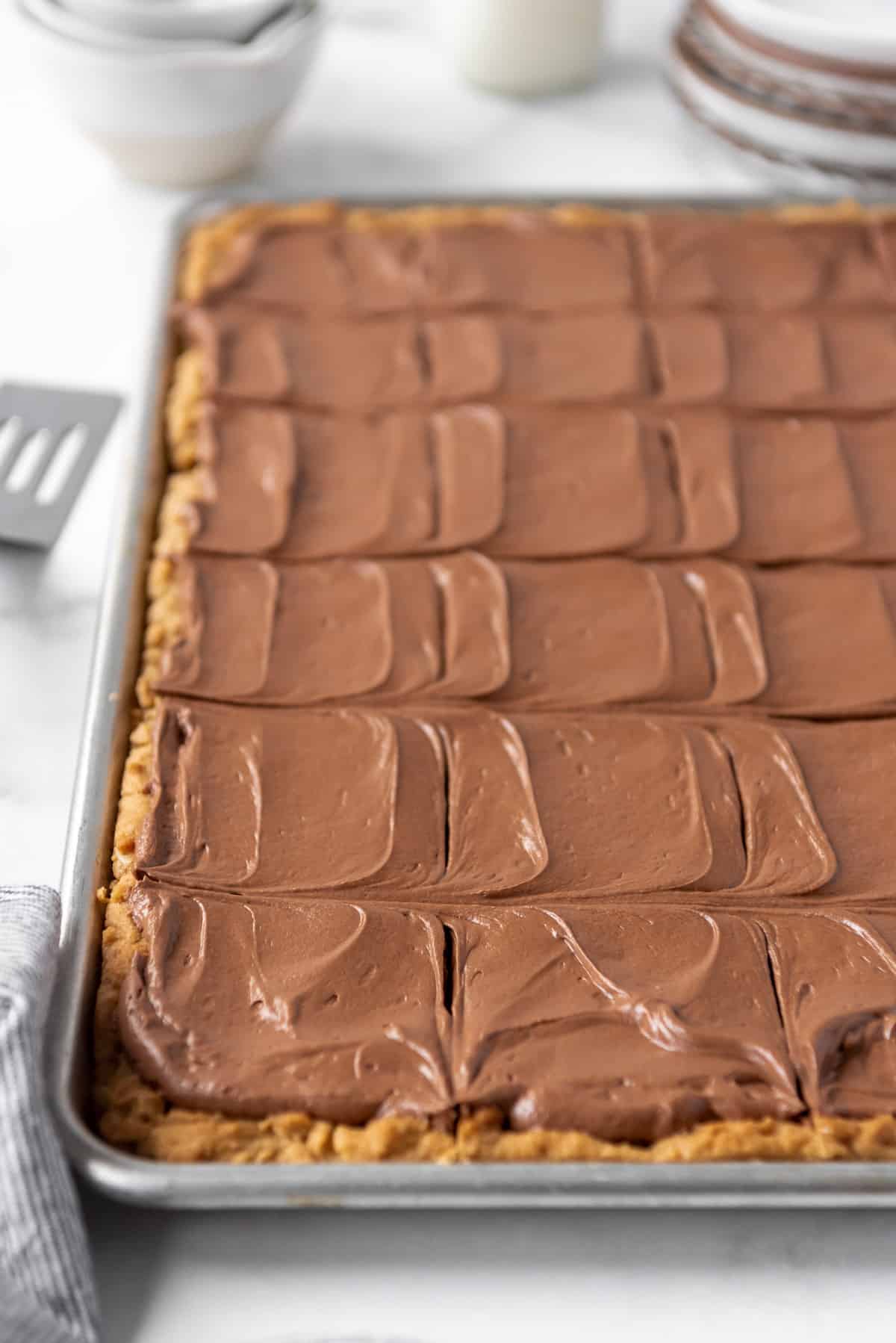 A large rimmed baking sheet with chocolate frosted peanut butter bars on it.
