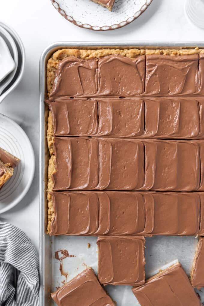 Chocolate frosted peanut butter bars that have been sliced into squares on a large baking sheet.