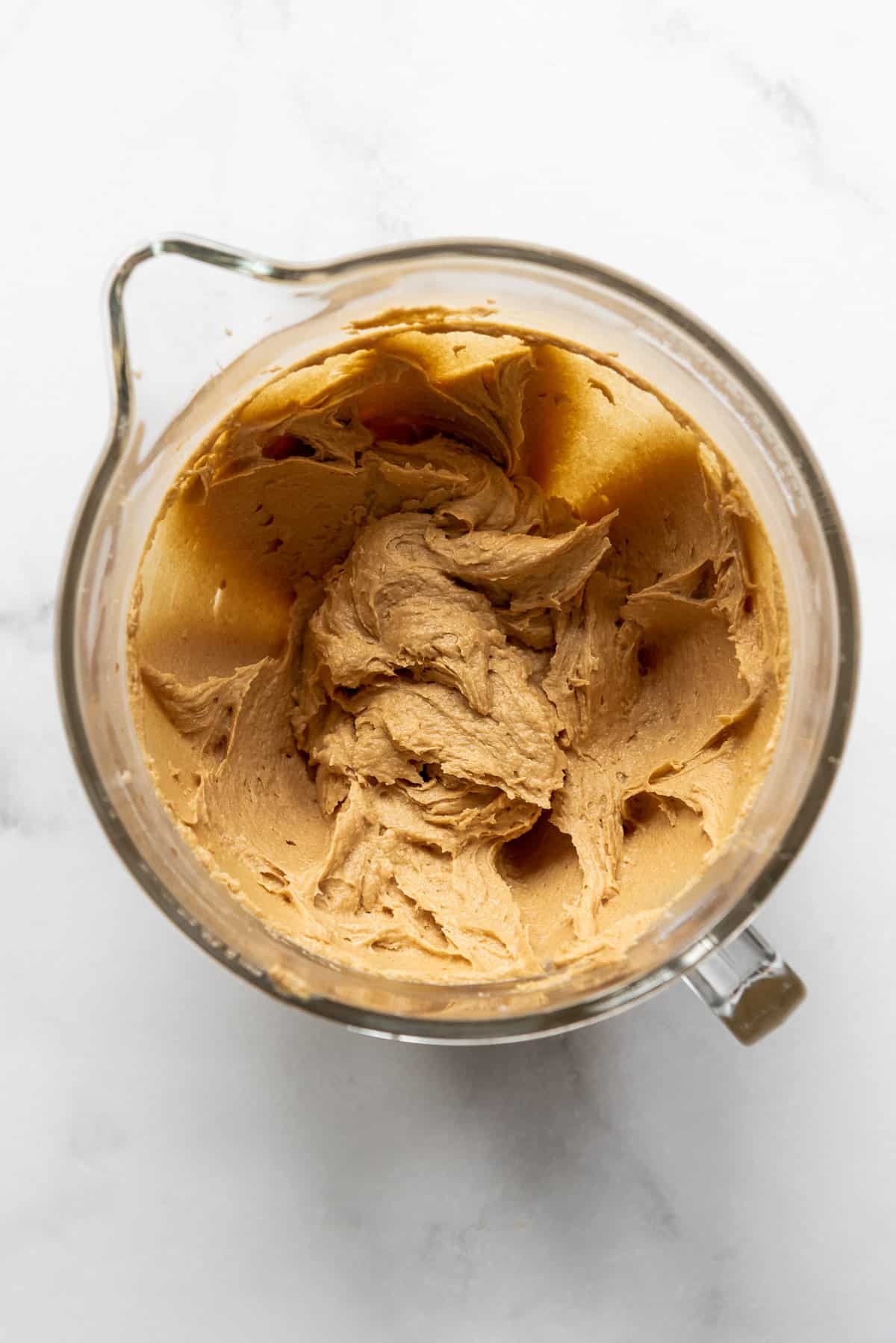 Creamed peanut butter, butter, sugar, eggs, and vanilla in a glass mixing bowl.