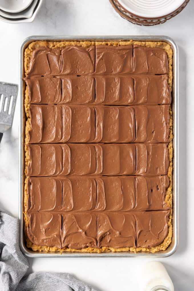 An overhead image of swirls of chocolate frosting on peanut butter bars that have been cut into squares.