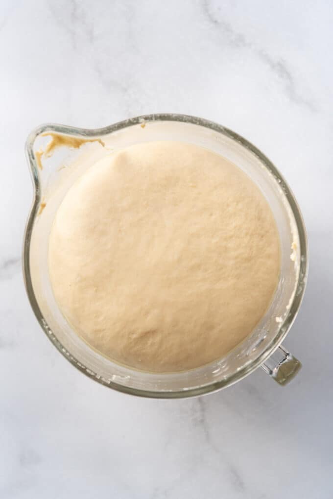 Brioche dough that has doubled in size in a glass bowl.