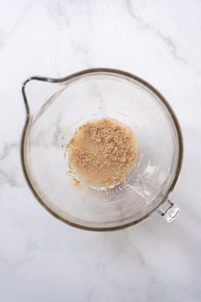 Combining warm water, yeast, and sugar in a bowl.