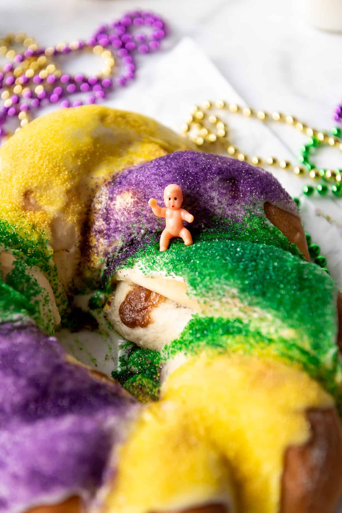 A miniature plastic toy baby on top of a king cake.