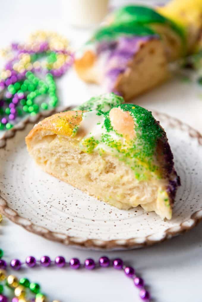 A slice of king cake with cream cheese filling on a plate.