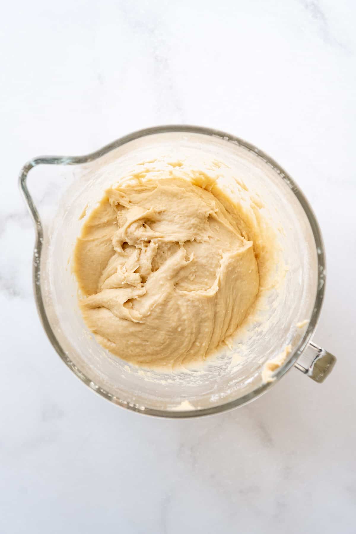 Kneaded brioche dough in a glass bowl.