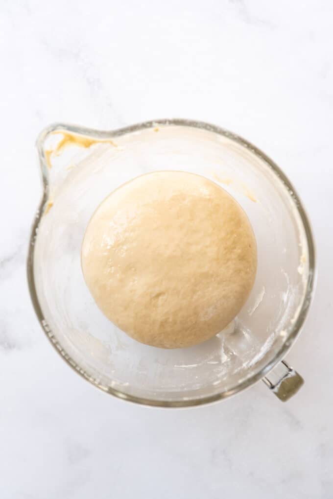 Brioche dough in a glass bowl ready to rise.