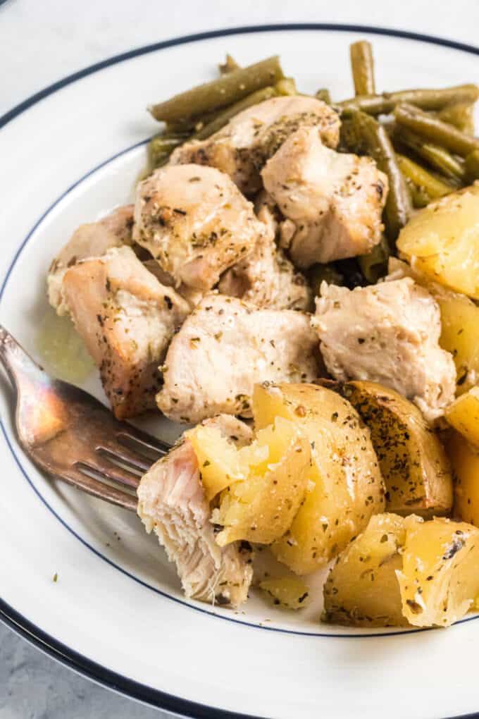Cooked chicken and potatoes on a white plate.