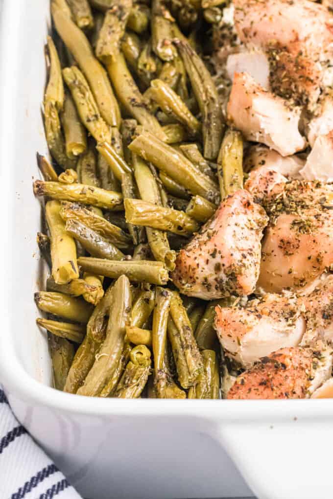 Roasted green beans and chicken in a white baking dish.