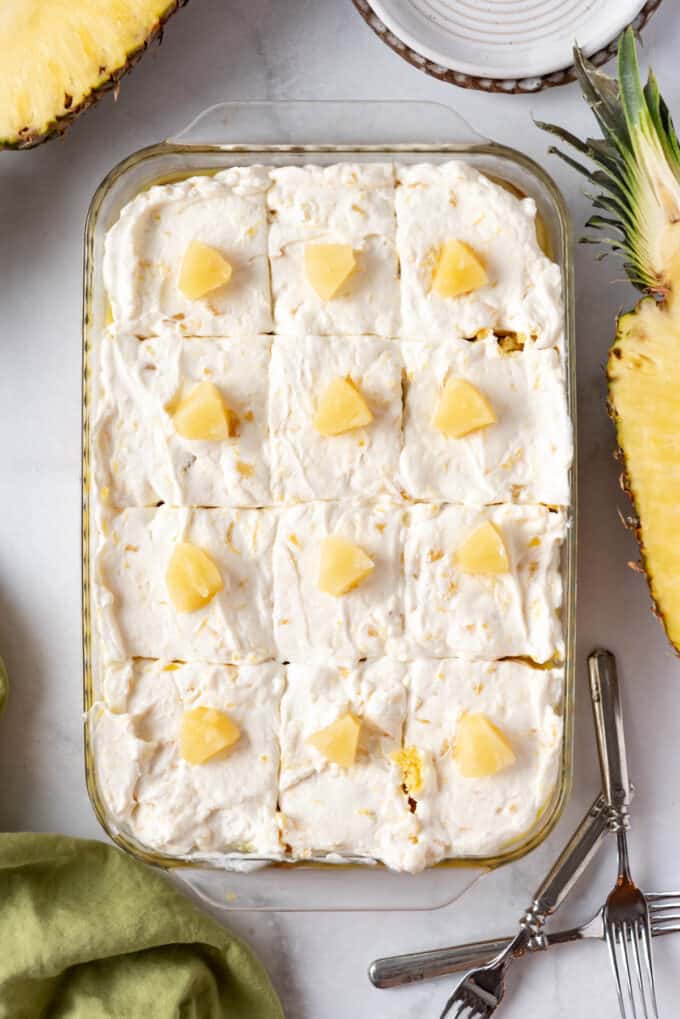 A pineapple poke cake sliced into twelve squares.